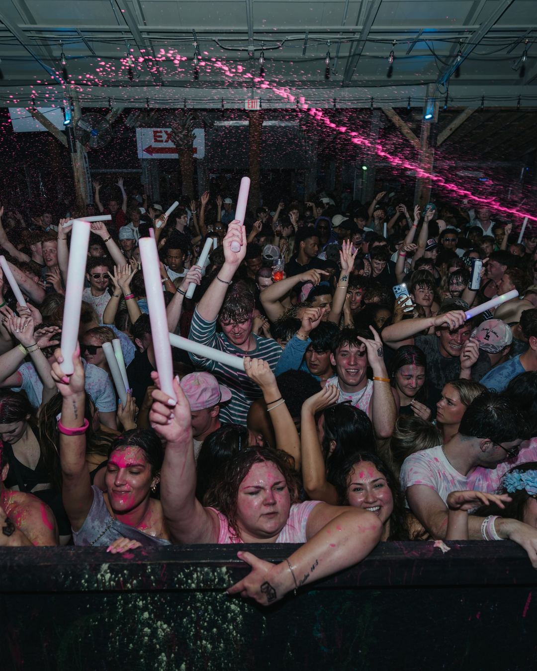 The front row of a spring break crowd holding up glow sticks