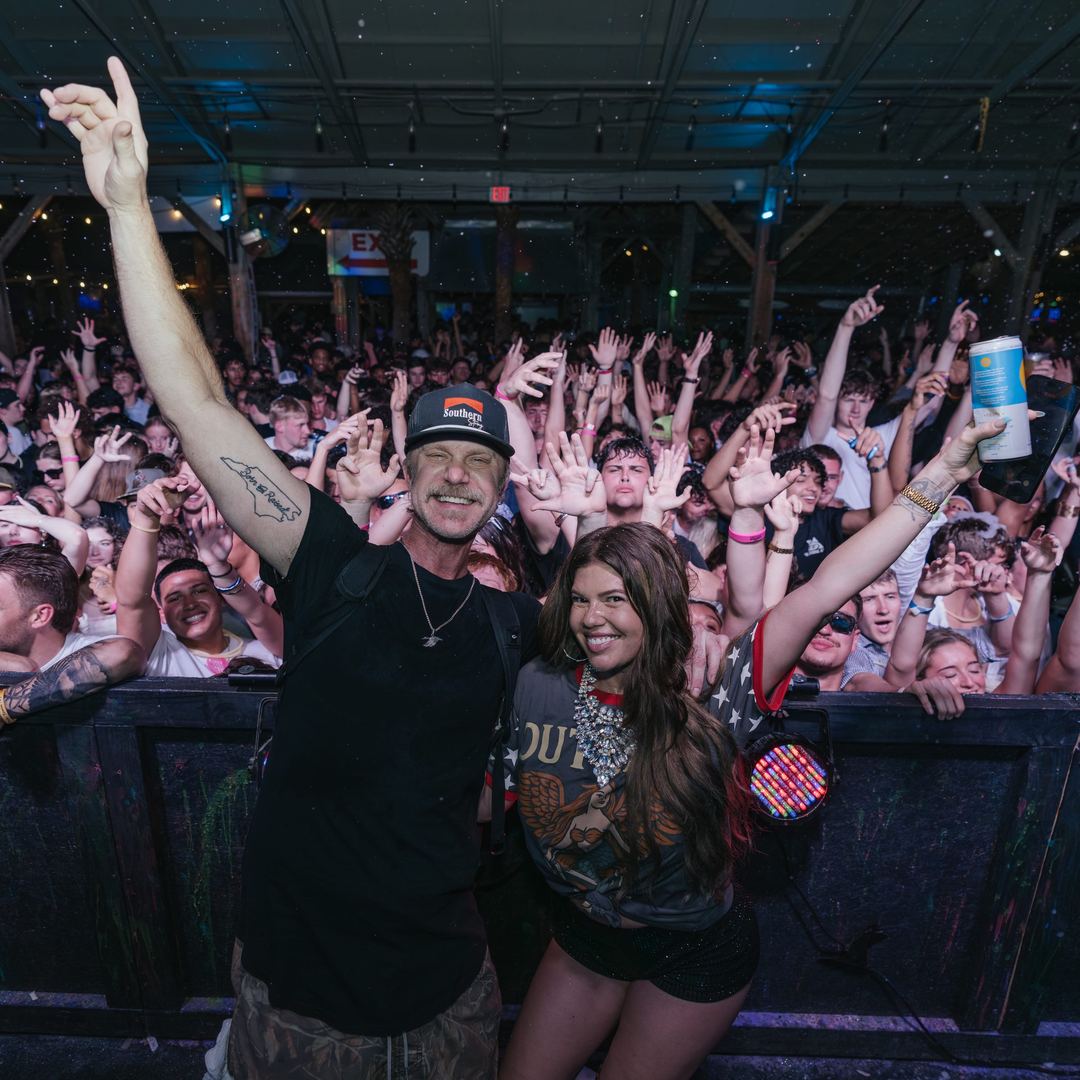 Two friends posing in front of a cheering spring break crowd