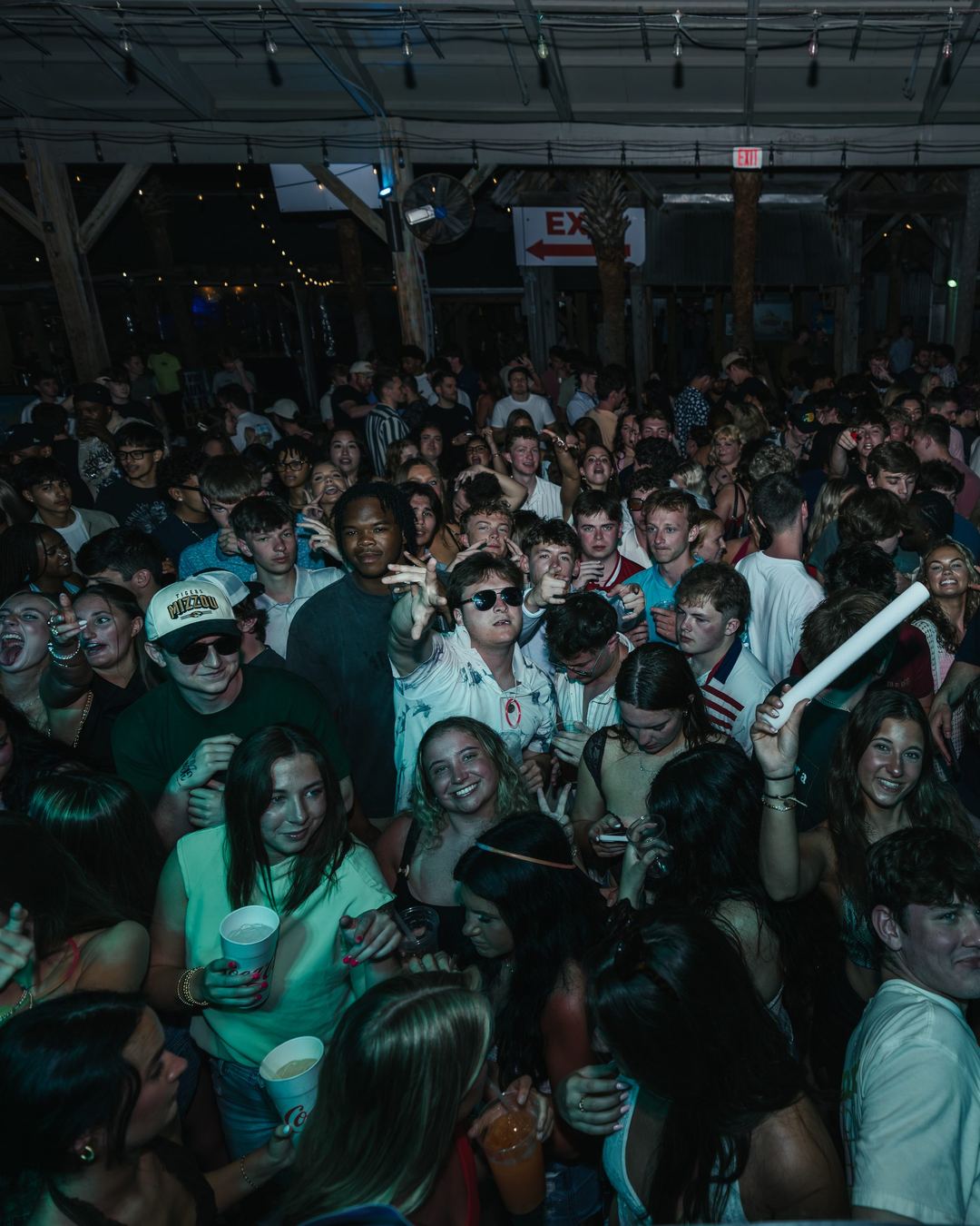 A night crowd at a spring break party, one person holding a glow stick