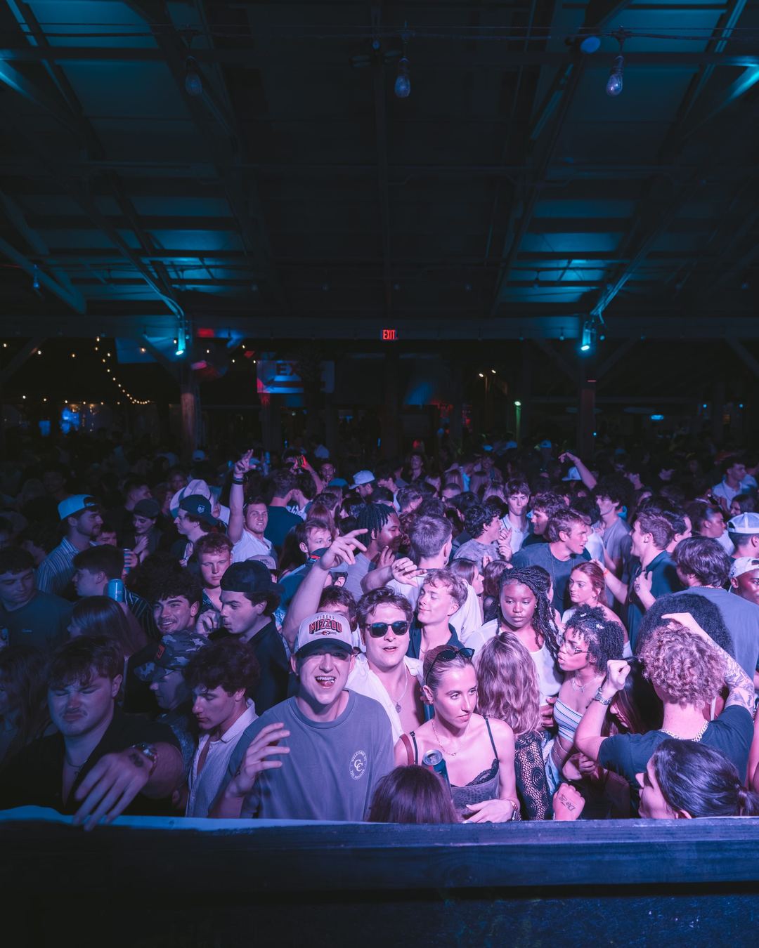 A dance floor full of spring breakers under purple lights